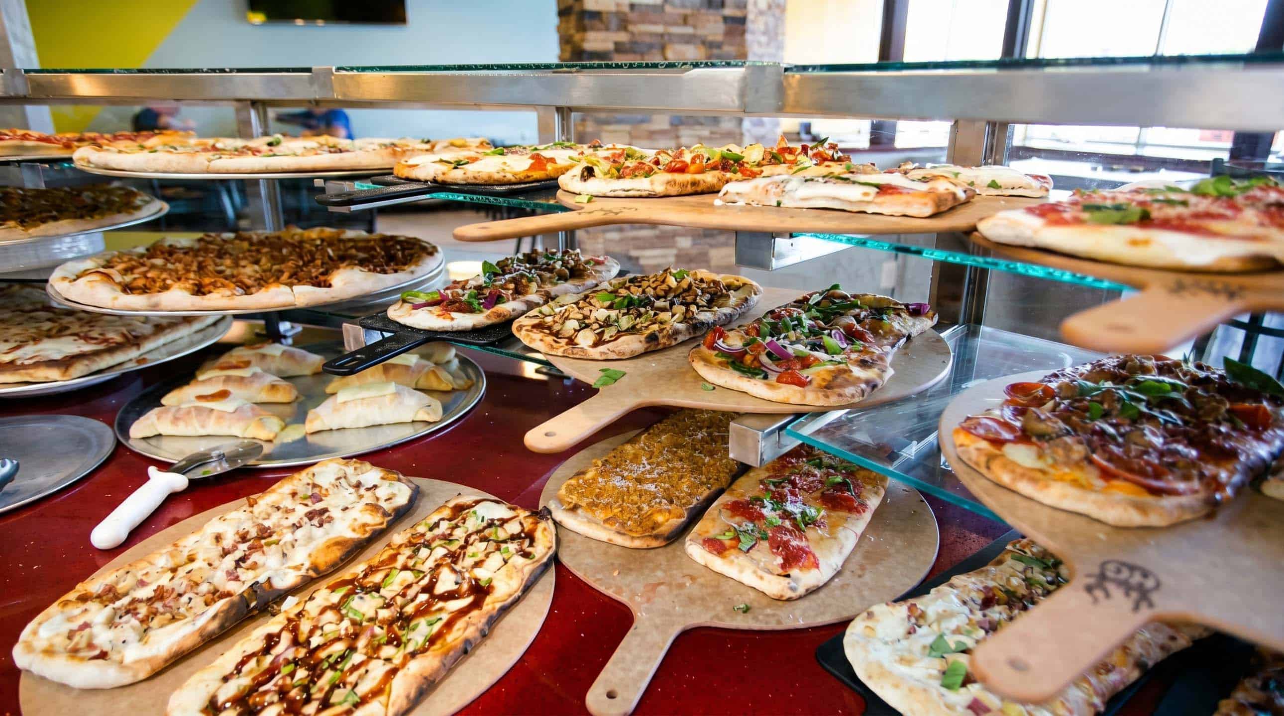 A variety of specialty pizzas displayed on wooden peels
