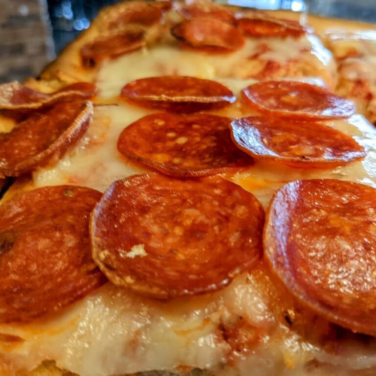 Pepperoni pizza on a green plate.